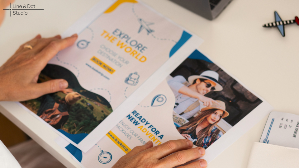Two travel brochure flyers lying on a table with the hands of a woman resting on it